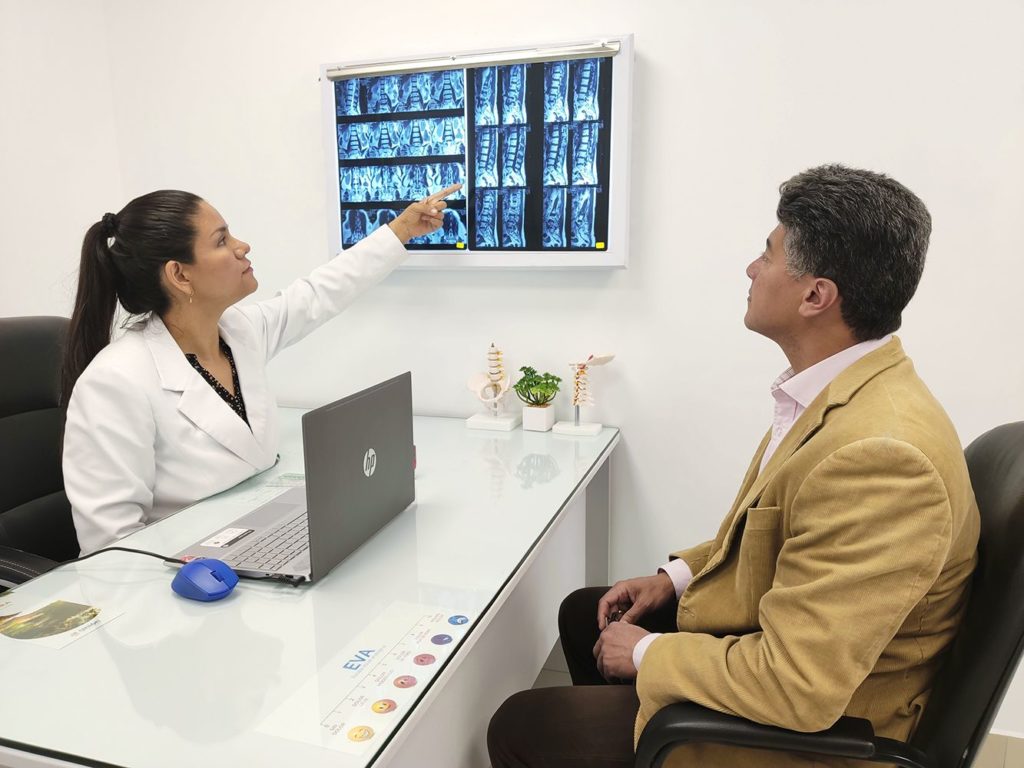 doctora mostrando radiografias de columna a paciente
